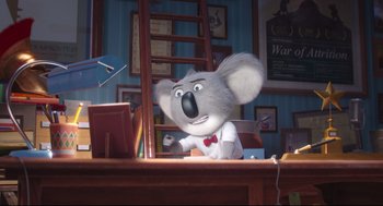 Movie still from “Sing” (2016), directed by Christophe Lourdelet – A cartoon koala sitting at a desk in front of a bookshelf; Medium shot, Low angle