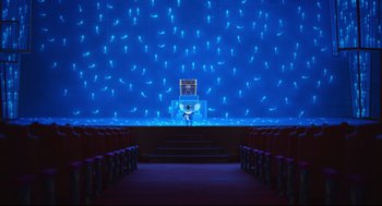 Movie still from “Sing” (2016), directed by Christophe Lourdelet – A stage lit up with blue lights in a theater; Extreme Wide shot, High angle