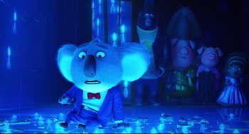 Movie still from “Sing” (2016), directed by Christophe Lourdelet – A stuffed animal is sitting in the middle of a room with other stuffed animals; Medium shot, Low angle
