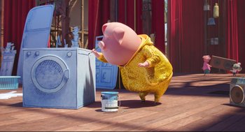 Movie still from “Sing” (2016), directed by Christophe Lourdelet – A pig in a raincoat is standing in front of a washing machine; Wide shot, Low angle