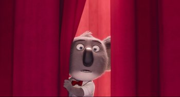 Movie still from “Sing” (2016), directed by Christophe Lourdelet – A koala bear is peeking out of a red curtain; Close Up shot, Low angle
