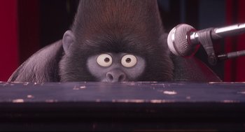 Movie still from “Sing” (2016), directed by Christophe Lourdelet – A monkey is holding a microphone in front of his face; Close Up shot, Low angle