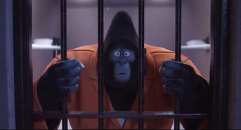 Movie still from “Sing” (2016), directed by Christophe Lourdelet – A gorilla in an orange jacket behind bars; Medium shot, High angle