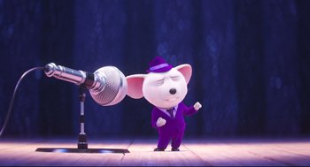 Movie still from “Sing” (2016), directed by Christophe Lourdelet – A cartoon mouse in a purple suit standing next to a microphone; Medium shot, Low angle