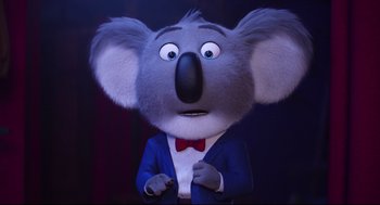 Movie still from “Sing” (2016), directed by Christophe Lourdelet – A koala character is wearing a blue suit and a red bow tie; Close Up shot, Low angle