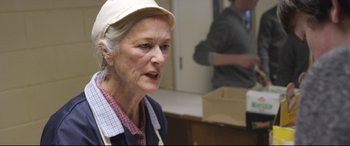 Movie still from “Sing Street” (2016), directed by John Carney – An older woman wearing a white hat in a kitchen; Close Up shot, Over the shoulder angle