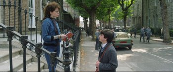 Movie still from “Sing Street” (2016), directed by John Carney – A woman is talking to a boy on the sidewalk; Medium shot, Over the shoulder angle
