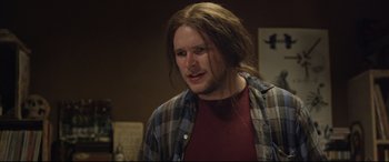 Movie still from “Sing Street” (2016), directed by John Carney – A man with long brown hair wearing a plaid shirt; Close Up shot, Over the shoulder angle