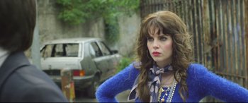 Movie still from “Sing Street” (2016), directed by John Carney – A woman with long brown hair wearing a blue sweater; Medium shot, Over the shoulder angle