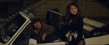 Movie still from “Sing Street” (2016), directed by John Carney – A man and a woman sitting in a car together; Medium shot, Over the shoulder angle