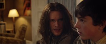 Movie still from “Sing Street” (2016), directed by John Carney – A man with long hair is looking at the camera; Close Up shot, Over the shoulder angle
