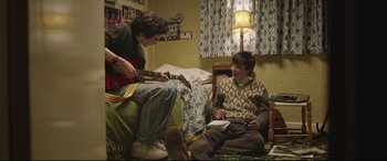 Movie still from “Sing Street” (2016), directed by John Carney – Two young men sitting on a bed playing a guitar; Medium shot, High angle