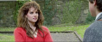 Movie still from “Sing Street” (2016), directed by John Carney – A woman in a red sweater standing in front of a stone wall; Close Up shot, Over the shoulder angle