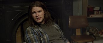 Movie still from “Sing Street” (2016), directed by John Carney – A man with long hair sitting in a chair; Close Up shot, Over the shoulder angle