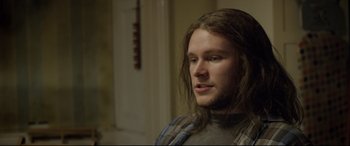 Movie still from “Sing Street” (2016), directed by John Carney – A man with long brown hair looking to his left; Close Up shot, Over the shoulder angle