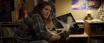 Movie still from “Sing Street” (2016), directed by John Carney – A man sitting in front of an album cover; Close Up shot, High angle