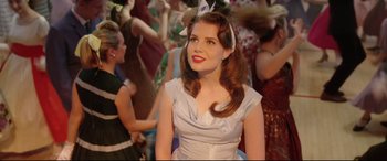 Movie still from “Sing Street” (2016), directed by John Carney – A woman in a white dress with a white bow in her hair; Medium shot, Over the shoulder angle