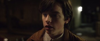Movie still from “Sing Street” (2016), directed by John Carney – A young man in a brown jacket looking to his left; Close Up shot, Over the shoulder angle