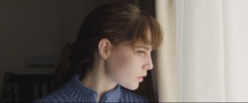 Movie still from “Sing Street” (2016), directed by John Carney – A woman looking out of a window at the outside; Close Up shot, Low angle