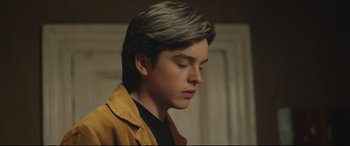 Movie still from “Sing Street” (2016), directed by John Carney – A young man with a gray hair and a black shirt; Close Up shot, Low angle