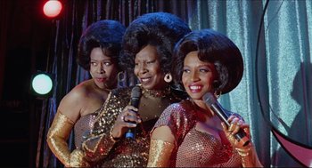 Movie still from “Sister Act” (1992), directed by Emile Ardolino – A group of three women singing into microphones; Medium shot, Low angle