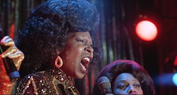 Movie still from “Sister Act” (1992), directed by Emile Ardolino – A woman singing into a microphone on a stage; Close Up shot, Low angle