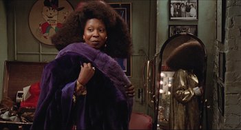 Movie still from “Sister Act” (1992), directed by Emile Ardolino – A woman in a purple coat standing in front of a mirror; Close Up shot, Low angle