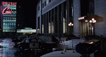 Movie still from “Sister Act” (1992), directed by Emile Ardolino – A police car parked in front of a large building at night; Extreme Wide shot, Low angle