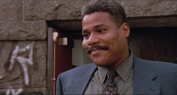 Movie still from “Sister Act” (1992), directed by Emile Ardolino – A person wearing a suit and tie; Close Up shot, Low angle