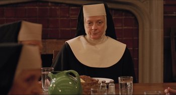 Movie still from “Sister Act” (1992), directed by Emile Ardolino – An older woman sitting at a table with a plate of food in front of her; Close Up shot, Over the shoulder angle