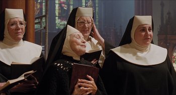 Movie still from “Sister Act” (1992), directed by Emile Ardolino – A nun is holding a book and talking on a phone; Medium shot, Low angle