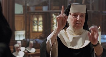Movie still from “Sister Act” (1992), directed by Emile Ardolino – An older woman in a nun's outfit is holding her finger up; Close Up shot, Low angle