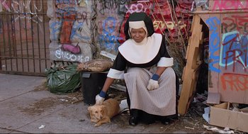 Movie still from “Sister Act” (1992), directed by Emile Ardolino – A nun kneeling down next to a brown dog; Wide shot, High angle