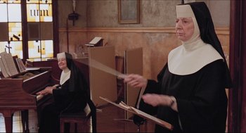 Movie still from “Sister Act” (1992), directed by Emile Ardolino – A nun is playing a musical instrument while another nun looks on; Medium shot, Low angle