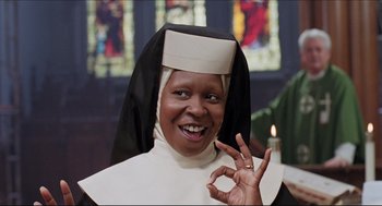 Movie still from “Sister Act” (1992), directed by Emile Ardolino – A nun giving the peace sign in front of a stained glass window; Close Up shot, High angle