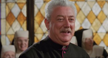 Movie still from “Sister Act” (1992), directed by Emile Ardolino – An older man with white hair wearing a black shirt; Close Up shot, Low angle