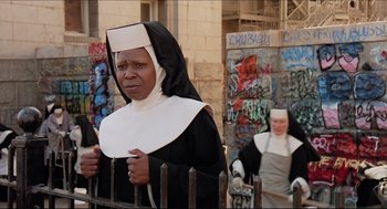 Movie still from “Sister Act” (1992), directed by Emile Ardolino – A woman dressed as a nun standing next to a fence; Medium shot, Low angle