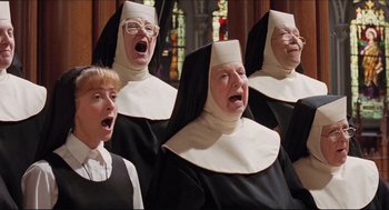 Movie still from “Sister Act” (1992), directed by Emile Ardolino – A group of nuns singing in front of a stained glass window; Medium shot, Low angle