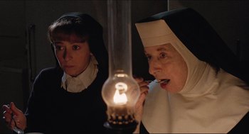 Movie still from “Sister Act” (1992), directed by Emile Ardolino – A nun is lighting a candle in front of another nun; Close Up shot, High angle