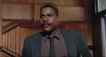 Movie still from “Sister Act” (1992), directed by Emile Ardolino – A man in a suit and tie with a mustache; Close Up shot, Low angle