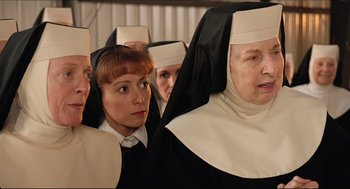 Movie still from “Sister Act” (1992), directed by Emile Ardolino – A group of people dressed as nuns in front of a building; Close Up shot, Over the shoulder angle
