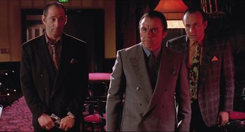 Movie still from “Sister Act” (1992), directed by Emile Ardolino – A group of men standing next to each other in a room; Medium shot, Low angle