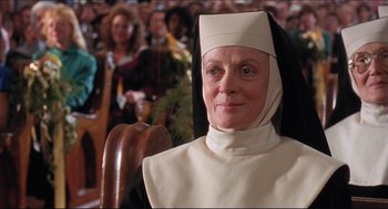 An older woman wearing a nun's outfit in front of an audience