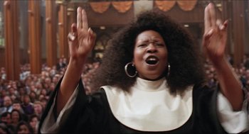 Movie still from “Sister Act” (1992), directed by Emile Ardolino – A woman in a nun's outfit holding her hand up in the air; Close Up shot, Low angle