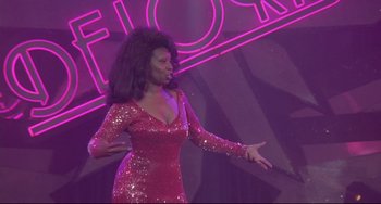 Movie still from “Sister Act 2: Back in the Habit” (1993), directed by Bill Duke – A woman in a red dress on a stage; Medium shot, Low angle