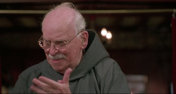 Movie still from “Sister Act 2: Back in the Habit” (1993), directed by Bill Duke – An older man wearing glasses and a monk's robe; Close Up shot, Over the shoulder angle