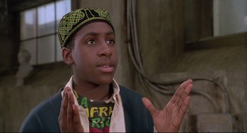Movie still from “Sister Act 2: Back in the Habit” (1993), directed by Bill Duke – A young man wearing a turban and a shirt with africa on it; Close Up shot, Low angle