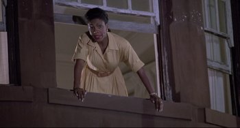Movie still from “Sister Act 2: Back in the Habit” (1993), directed by Bill Duke – A woman in a yellow dress looking out of a window; Medium shot, Low angle