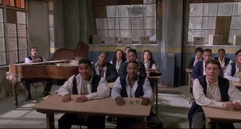 Movie still from “Sister Act 2: Back in the Habit” (1993), directed by Bill Duke – A group of people sitting at a table in front of a window; Wide shot, High angle