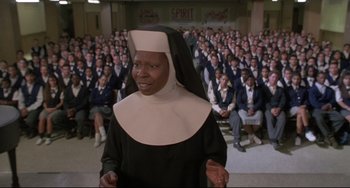 Movie still from “Sister Act 2: Back in the Habit” (1993), directed by Bill Duke – A woman dressed as a nun standing in front of a group of people; Medium shot, High angle